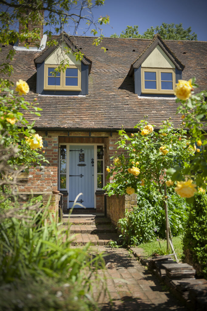 Country house with brown casement windows and blue entrance doors