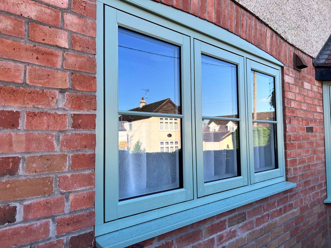side view chartwell green flush sash window installed within red brick wall
